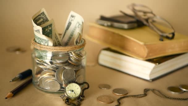 Books with glass penny jar filled with coins and banknotes. Tuition or education financing concept. Scholarship money. — Stock Video