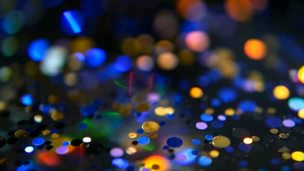 Defocused shimmering multicolored glitter confetti, black background. Holiday abstract festive bokeh light spots. — Stock Video