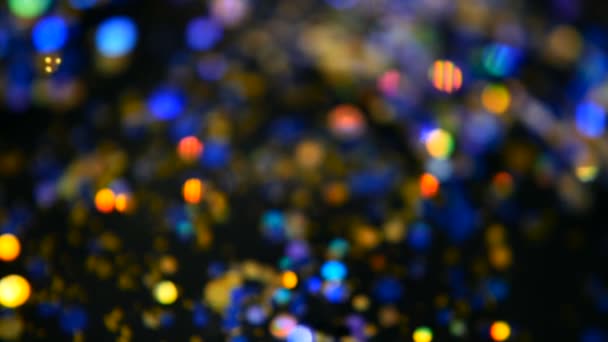 Intreepupil glinsterende veelkleurige glitter confetti, zwarte achtergrond. Vakantie abstracte feestelijke bokeh licht vlekken. — Stockvideo