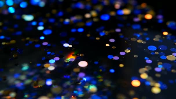 Oskärpa skimrande mångfärgade glitter konfetti, svart bakgrund. Holiday abstrakt festliga bokeh ljusa fläckar. — Stockvideo