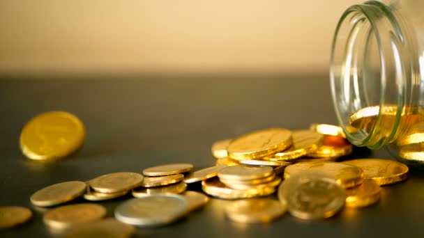 Close-up ainda vida com moedas de ouro na mesa preta e girando centavo. As moedas amarelas caíram do jarro . — Vídeo de Stock