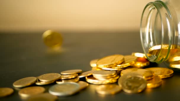 Крупный план натюрморт с золотыми монетами на черном столе и вращающимся пенни. Желтые монеты выпали из банки . — стоковое видео