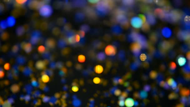 Intreepupil glinsterende veelkleurige glitter confetti, zwarte achtergrond. Vakantie abstracte feestelijke bokeh licht vlekken. — Stockvideo