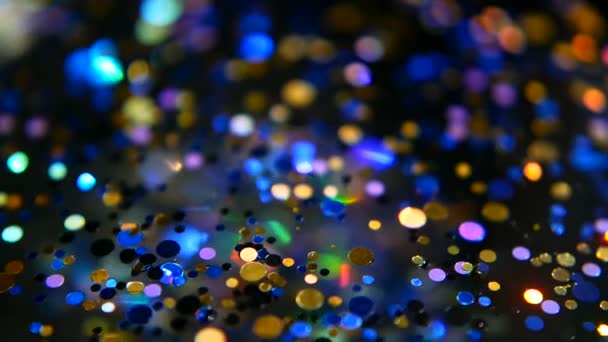 Defokussiert schimmerndes buntes Glitzerkonfetti, schwarzer Hintergrund. Urlaub abstrakte festliche Bokeh Lichtpunkte. — Stockvideo