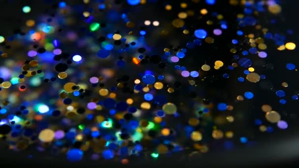 Confetti glitter multicolore sfocati e luccicanti, sfondo nero. Vacanze astratto festivo bokeh punti luce . — Video Stock