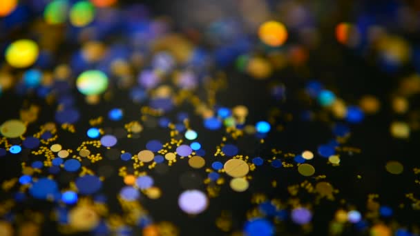 Confetti glitter multicolore sfocati e luccicanti, sfondo nero. Vacanze astratto festivo bokeh punti luce . — Video Stock