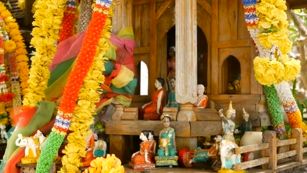 Houten miniatuur voogd geest huis. Klein boeddhistische tempel heiligdom, kleurrijke bloemenslingers. San phra phum. — Stockvideo