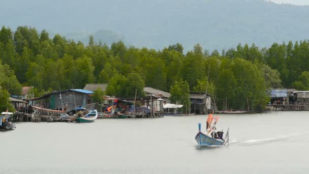 KHANOM, THAILAND - SEPTEMBER 21, 2018.渔民村的小船在红树林的河水上。传统的亚洲景观。穷困潦倒的房子。渔船 — 图库视频影像