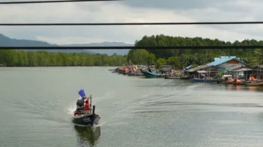 KANOM, THAILAND - 21 Eylül 2018. Mangrovlardaki nehir kıyısındaki balıkçı köyünde küçük tekneler. Geleneksel Asya manzarası. Barakalarda fakir evler. Balıkçılık