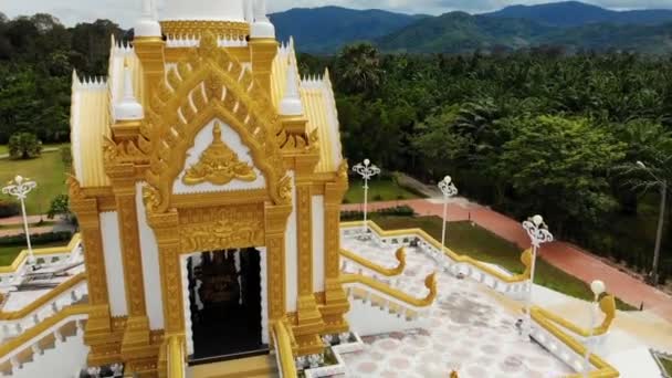 Drone view of beautiful golden temple in green forest in Thailand. Palm woods. Khanom. Sacred stupa or pagoda — Stock Video