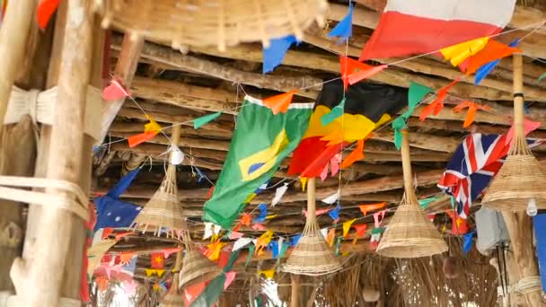 Banderas nacionales decorativas de diferentes países colgando de cuerdas en bungalow tropical de madera. Exótica rasta bar interior. Casa de playa de verano en la isla de Koh Phangan, Tailandia — Vídeo de stock