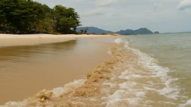 Côte sablonneuse blanche et mer bleue calme. paradis tropical idyllique paysage insulaire exotique avec des arbres verts et un océan ondulant tranquille sur fond de montagnes et de ciel. Surf calme, vue basse au-dessus de l'eau . — Video