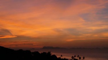 Görkemli tropikal turuncu yaz timelapse günbatımı dağlar siluetleri ile deniz üzerinde. Okyanusu Adaları üzerinde dramatik alacakaranlık, altın bulutlu gökyüzü hava görünümünü. Alacakaranlıkta canlı deniz manzarası doğal arka plan