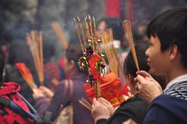 HONG KONG - 22th FEBRUARY, 2015: Crowd of people with aromatic sticks near temple, View of crowded square of people carrying burning sticks in front of Wong Tai Sin temple. Celebrating New Year. clipart