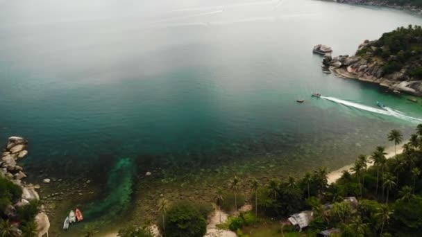 Aereo drone vista dall'alto di sabbia bianca tropicale paradiso esotico piccola riva nell'isola di Koh Prangan, Thailandia. Piccole barche sulla superficie dell'oceano. Carina spiaggia remota con pietre vulcaniche e palme da cocco verdi — Video Stock