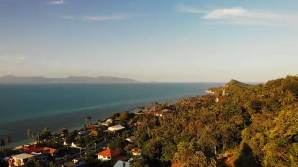 Luchtfoto drone weergave. Heuvelachtige kust gewassen door blauwe zee. Uit de bovenstaande weergave van Koh Samui kust met huizen, weg- en palm bomen gewassen door de kalme blauwe oceaan op achtergrond van bergen en duidelijke hemel. — Stockvideo