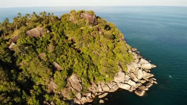 Pohled shora letecké dron exotický ráj tropické pobřežním útesu s lávovými kameny pokryté zelenou džungli deštného pralesa a coconun dlaně vymyje klidný oceán nebo na moři, ostrov Koh Prangan, Thajsko. — Stock video