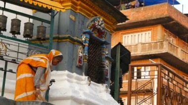 KATHMANDU, NEPAL - 8 EKİM 2018 Tapınak merdivenlerini süpüren yaşlı kadın. Renkli, geleneksel Hint kumaşlı yaşlı kadın, Swayambhunath Stupa. Kutsal Pagoda, sembol. Gün batımı ligth