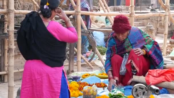 BHAKTAPUR, KATHMANDU, NEPAL - 18 de octubre de 2018 Personas asiáticas que venden productos en ropa nacional, mercado de templos de frutas de la mañana. Vida diaria del comercio callejero, ciudad antigua oriental después del terremoto. — Vídeos de Stock