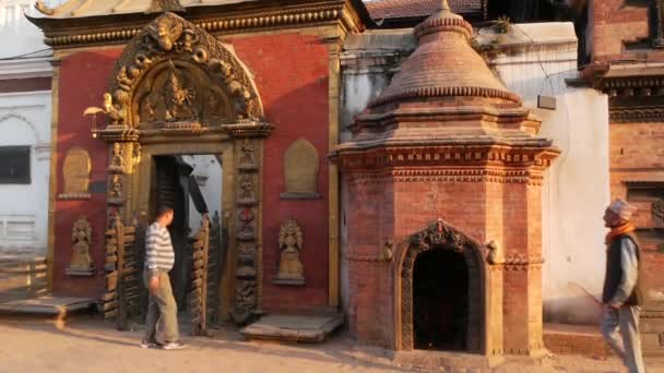 BHAKTAPUR, KATHMANDU, NEPAL - 18 de octubre de 2018 Newar personas visitando Palacio Real de 55 ventanas, puerta de oro, plaza Durbar para adorar. Religiosa vida cotidiana, ciudad antigua oriental después del terremoto — Vídeo de stock