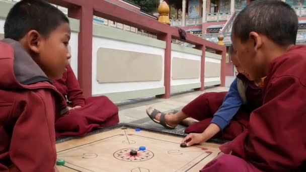 BHAKTAPUR, KATHMANDU, NEPAL - 18 Outubro 2018 Jovens meninos alegres jogando jogo de mesa no quintal do templo. Sorrindo monges budistas no mosteiro das crianças na Ásia em roupão . — Vídeo de Stock