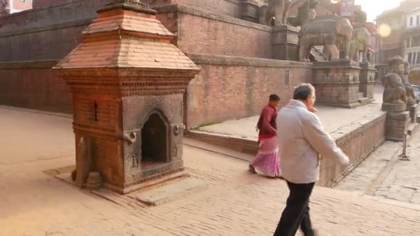 BHAKTAPUR, KATHMANDU, NEPAL - 2018 년 10 월 18 일 지진 이후 고대 도시의 보행자의 일 일 교통. 국가의 옷을 입은 현지 주민들이 사원 근처 거리를 행진하고 있다 — 비디오