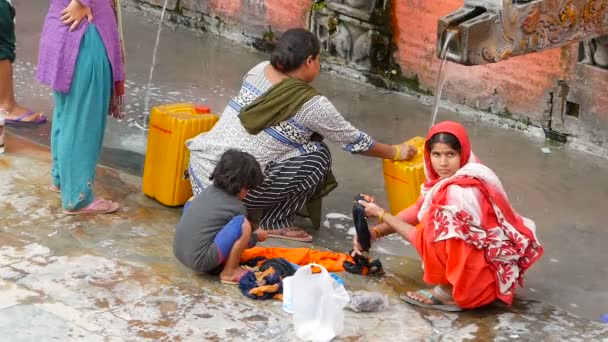 LALITPUR PATAN, NEPAL - 12 DE OUTUBRO DE 2018 Pessoas lavando perto da parede do templo. Vista de mulheres lavando cabelo e roupas com água de guindastes de pedra envelhecidos na parede de tijolo na rua. Vida de rua de Kathmandu — Vídeo de Stock