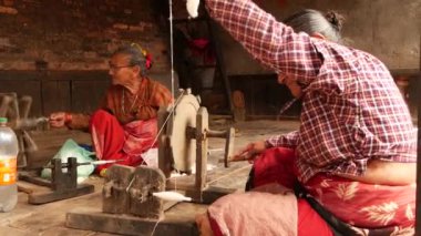 Bhaktapur, Kathmandu, Nepal-18 Ekim 2018 yaşlı etnik kadınlar Eski geleneksel ekipmanlarla Spinning iplik. Bahçede oturan yaşlı kadınlar. Günlük yaşam, deprem sonrası oryantal antik şehir