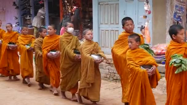 BHAKTAPUR, KATHMANDU, NEPAL - 18 Ekim 2018 Genç Budist rahipler geçit töreni bağış toplamak için yürüyor, çocuklar bağış topluyorlar. Günlük sokak hayatı, depremden sonra antik doğu şehri. — Stok video