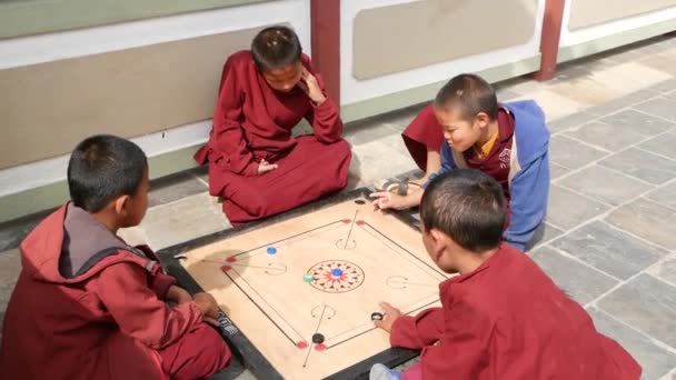 Bhaktapur, Kathmandu, Nepal - 18 oktober 2018 glada unga pojkar spelar bordsspel i templet gården. Ler buddhistiska munkar i barnens kloster i Asien i robe. — Stockvideo