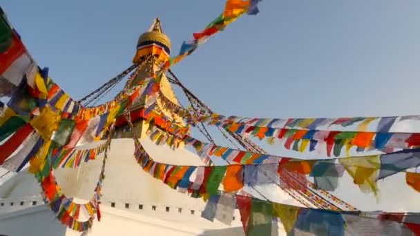 Flagi modlitewne kolorowy latający na wietrze w Boudhanath Stupa, Święty Pagoda, symbol Nepalu i Kathmandu z golgen oczami buddów. Zachód słońca ligth — Wideo stockowe