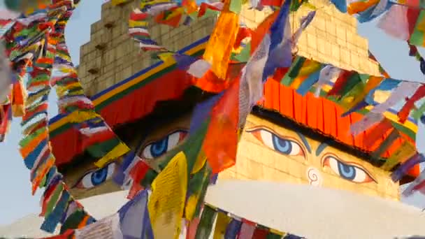 Colorful prayer flags flying in the wind at Boudhanath Stupa, Holy Pagoda, symbol of Nepal and Kathmandu with golgen Buddhas Eyes. Sunset ligth — Stock Video