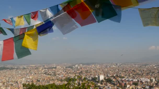 Waving flag modlitewnych przeciwko gród. Widok macha flagi modlitewne wielobarwny na ciągi nad panoramę miasta doliny Kathmandu, Swayambhunath Stupa, świątyni małp, Nepal. — Wideo stockowe