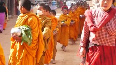 BHAKTAPUR, KATHMANDU, NEPAL - 18 Ekim 2018 Genç Budist rahipler geçit töreni bağış toplamak için yürüyor, çocuklar bağış topluyorlar. Günlük sokak hayatı, depremden sonra antik doğu şehri.