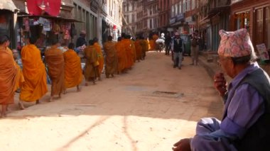 BHAKTAPUR, KATHMANDU, NEPAL - 18 Ekim 2018 Genç Budist rahipler geçit töreni bağış toplamak için yürüyor, çocuklar bağış topluyorlar. Günlük sokak hayatı, depremden sonra antik doğu şehri.