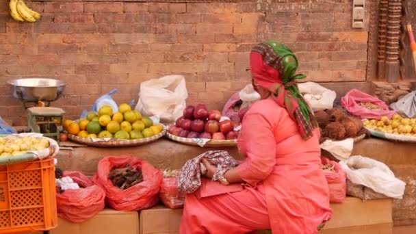 BHAKTAPUR, KATHMANDU, NEPAL - 18 Outubro 2018 Os asiáticos que vendem mercadorias em roupas nacionais, frutas da manhã legumes templo mercado. Vida diária do comércio de rua, cidade antiga oriental após o terremoto. — Vídeo de Stock