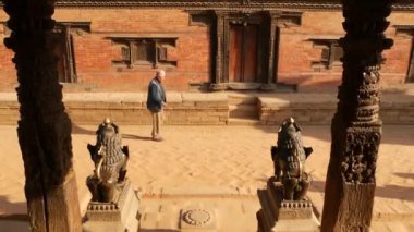 BHAKTAPUR, KATHMANDU, NEPAL - 18 Ekim 2018 Doğu antik kentinde deprem sonrası yaya trafiği. Ulusal giysili yerel newar insanları tapınağın yakınındaki sokaklara gidiyorlar.