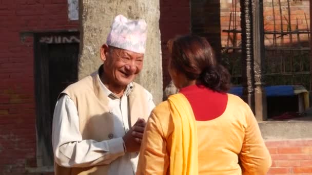 BHAKTAPUR, KATHMANDU, NEPAL - 18 Outubro 2018 Homem asiático e mulher idosa sênior em roupas nacionais e bom humor feliz sorrindo, tomando. Cidadãos vida diária, oriental antiga cidade após terremoto — Vídeo de Stock