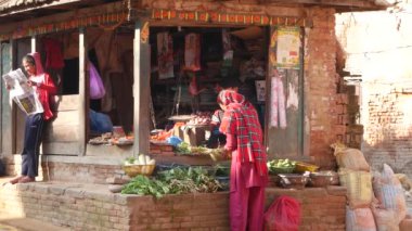 BHAKTAPUR, KATHMANDU, NEPAL - 18 Ekim 2018 Asyalılar ulusal giysiler ve sabah sebze tapınağı pazarında ürün satıyorlar. Günlük ticaret hayatı, depremden sonra antik doğu şehri..