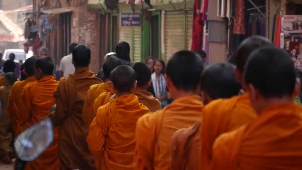 BHAKTAPUR, KATHMANDU, NEPAL - 18 október 2018 Fiatal buddhista szerzetesek felvonulás felvonulás séta alamizsnáért, gyerekek gyűjtése jótékonysági ajánlatok. Napi utcai élet, keleti ókori város földrengés után — Stock videók