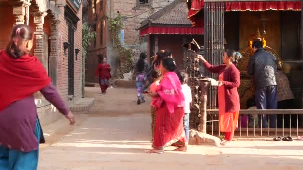 BHAKTAPUR, KATHMANDU, NEPAL - 18. října 2018 Noví lidé navštěvují hinduistický chrám za účelem uctívání v tradičních šatech. Náboženský každodenní život občanů, orientální starobylé město po zemětřesení — Stock video