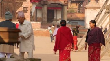 BHAKTAPUR, KATHMANDU, NEPAL - 18 Ekim 2018 Asyalı erkek ve yaşlı kadın ulusal kıyafetler içinde mutlu bir şekilde gülümsüyor, alıyor. Vatandaşlar günlük yaşam, depremden sonra antik doğu şehri.
