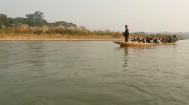 CHITWAN Ulusal Parkı, NEPAL - 10 Ekim 2018 Turistler nehirde kanoyla geziyorlar. Safari gezisi sırasında yeşil nehirde yüzen turistlerle dolu uzun tahta bir kano..