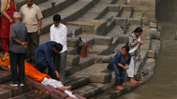 KATHMANDU, NEPAL - 8 OCTOBER 2018: Warga Hindu lokal, upacara kremasi tradisional di ghat yang terbakar di tepi Sungai Bagmati yang suci di kuil Pashupatinath — Stok Video