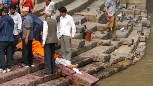 KATHMANDU, NEPAL - 8 OCTOBER 2018: Warga Hindu lokal, upacara kremasi tradisional di ghat yang terbakar di tepi Sungai Bagmati yang suci di kuil Pashupatinath — Stok Video