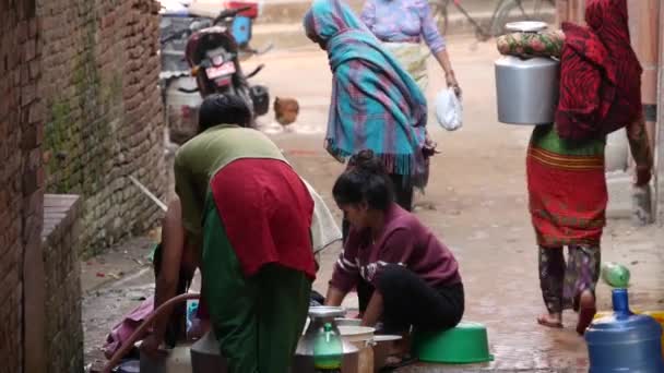 BHAKTAPUR, NEPAL - 13. OKTOBER 2018 Menschen waschen sich in der Nähe der Tempelmauer. Ansicht von Frauen, die Haare und Kleidung mit Wasser aus alten Steinkränen in Ziegelmauern auf der Straße waschen. Straßenleben in Kathmandu — Stockvideo