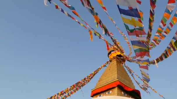 Színes ima zászlók repül a szél Boudhanath sztúpájának, Szent Pagoda, jelképe Nepál és Kathmandu golgen Buddhák szemét. Naplemente ligth — Stock videók