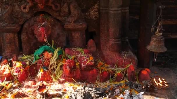 Schrijn met beeldhouwwerk en kaarsen branden. Hindoetempel heiligdom in openlucht met beeldhouwwerk van Ganesha en brandende kaarsen in zonlicht, Nepal. — Stockvideo
