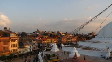 KATHMANDU, NEPAL - 12 Ekim 2018. Boudhanath Stupa ile şehir meydanının panoraması. Himalaya dağlarına karşı güzel bir doğu şehri manzarası. Turistler ve inananlar gün batımında yürüyorlar