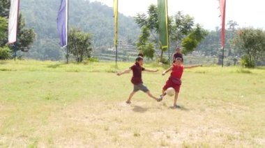 BHAKTAPUR, KATHMANDU, NEPAL - 18 Ekim 2018 Yeşil çayır üzerinde futbol oynayan Budist rahipler. Bir grup çocuk manastırı Asya 'daki tapınak bahçesinde yeşil çimlerde koşuyor..